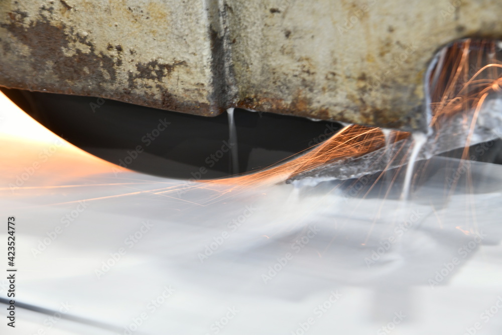 Metal processing by grinding on a surface grinding machine with sparks and water cooling.