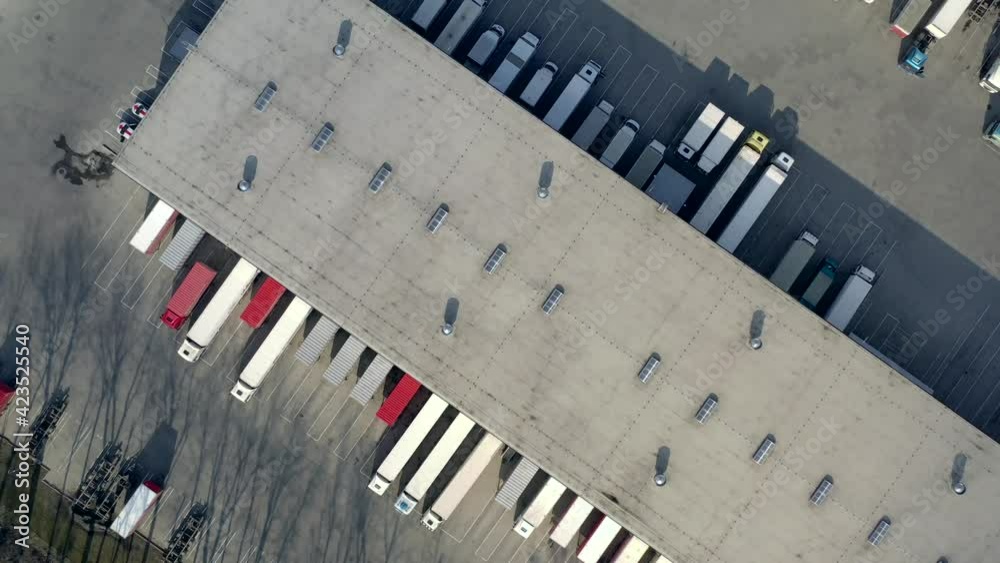 Aerial view of goods warehouse. Logistics center in industrial city zone from above. Aerial view of trucks loading at logistic center. View from drone.