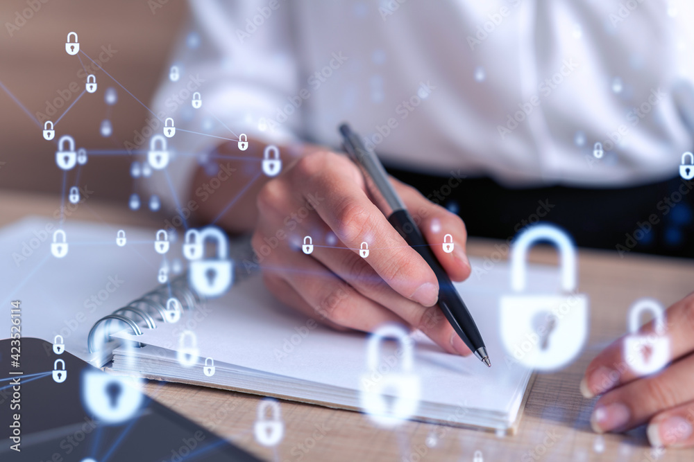 Businesswoman is taking notes of clients needs to protect cyber security from hacker attacks and save clients confidential data. Padlock Hologram icons over the typing hands. Formal wear Businesswoman is taking notes of clients needs to protect cyber security from hacker attacks and save clients confidential data. Padlock Hologram icons over the typing hands. Formal wear