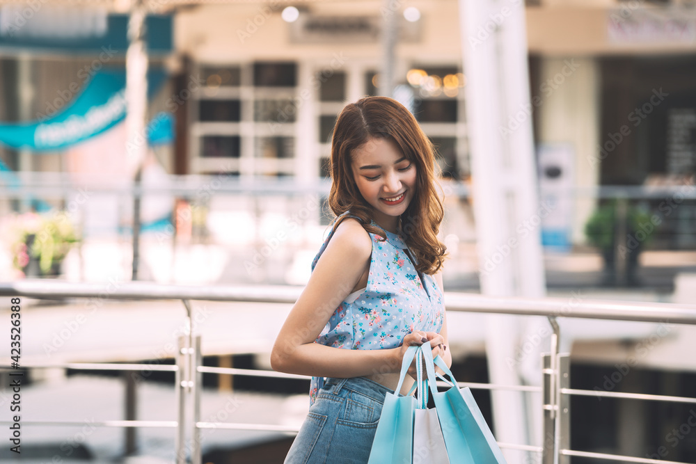 Happy young adult asian woman with shopping bags on day.