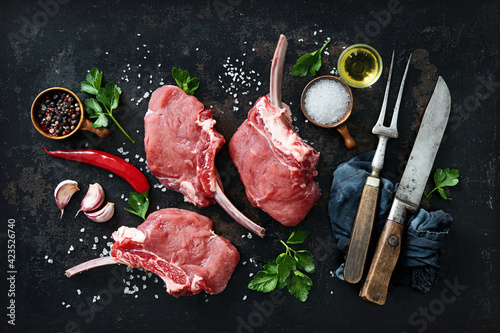 Raw veal Frenched Racks meat with ingredients on rustic dark background photo