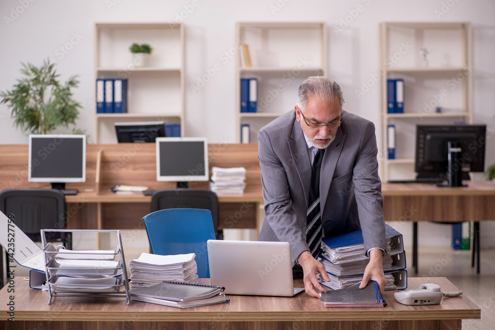 Old male employee unhappy with excessive work in the office Old male employee unhappy with excessive work in the office