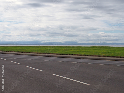 The coast road at crosby in merseyside with grass surrounding the sea at the mouth of the river mersey