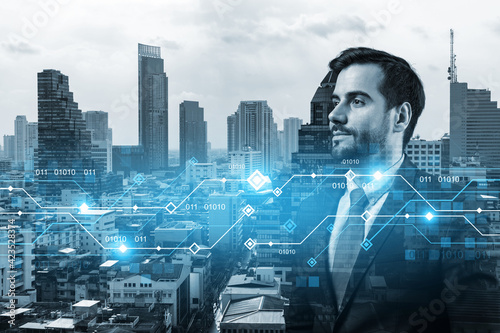 Caucasian young businessman pondering on technology at business process to achieve tremendous growth in commerce. Worldwide process to conduct transactions. Tech hologram icons over Bangkok background