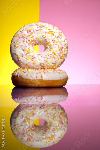 deux donuts blanc sur fond bicolore rose et jaune avec reflet