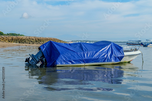 Fishing boat wrapped in blue plastic cloth. Fishing boats that are not operating are anchored on the coast.