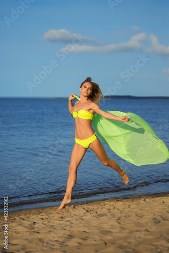 Woman at the beach holding sarong up in the air