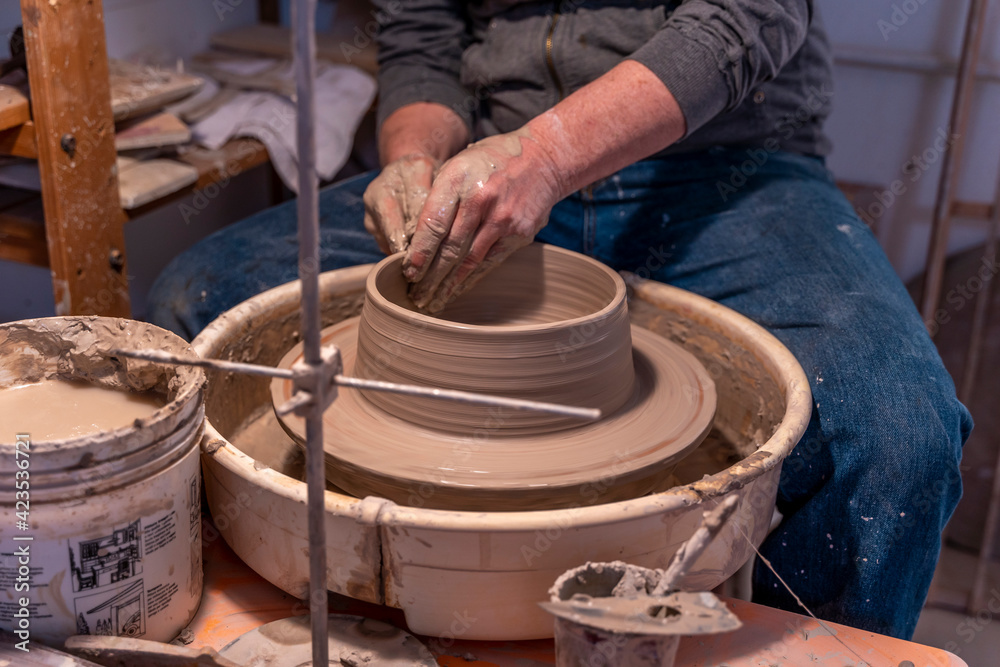 close-up on male hands working on a potters wheel to make a bowl