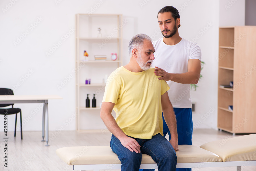 Old male patient visiting young male doctor chiropractor
