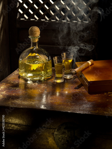 Close up view of bottle of tequila anejo and cigar on color background