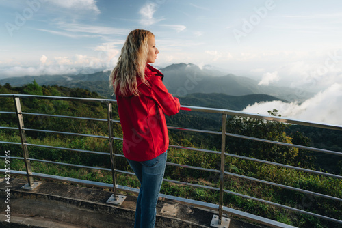 A woman wearing a red jacket standing at amazing landscap on a high