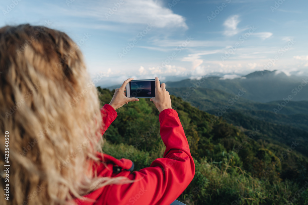 A woman wearing a red jacket make photo of an amazing landscape on a highest point of in Thailand