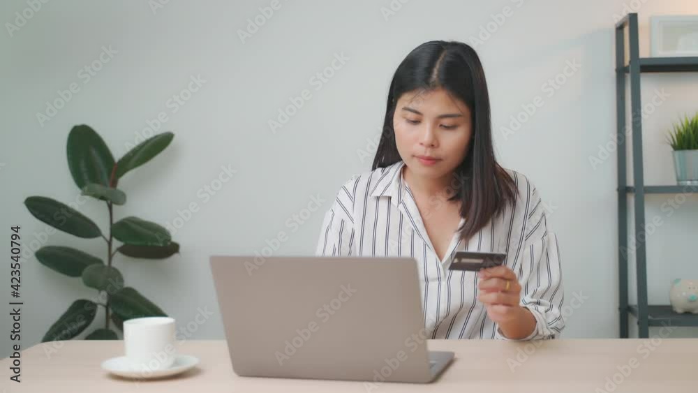 Young attractive happy Asian woman is using laptop or tablet for shopping and paying online by credit cards in her hand, online purchases content, commerce on the Internet shop, social distancing. Young attractive happy Asian woman is using laptop or tablet for shopping and paying online by credit cards in her hand, online purchases content, commerce on the Internet shop, social distancing.