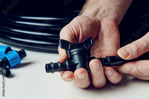 Preparing for planting in early spring. Male hands in the frame hold a faucet for drip irrigation. DIY drip irrigation system assembly