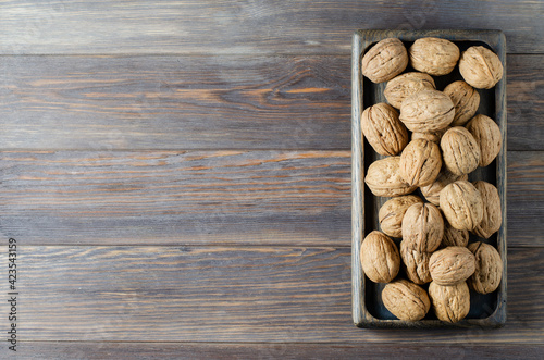 Walnuts on a dark brown wooden background. Flat top view, copy space.
