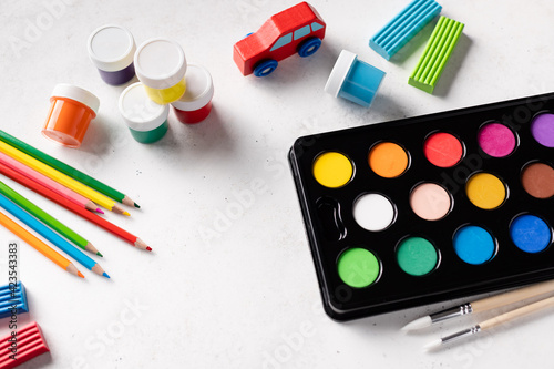 Colorful paints set on white background. Watercolor paints in box, color pencils, gouache cans, clay. Creativity and education concept. copy space