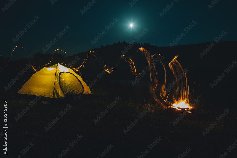 long exposure bonfire with yellow tent on background