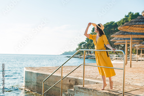 young pretty woman in yellow sundress at sea beach