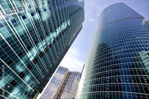 Bottom up view of modern office buildings in the city s business district. Glass facades of skyscrapers with contrasting highlights and reflections. Economy development  finance and business concept. 