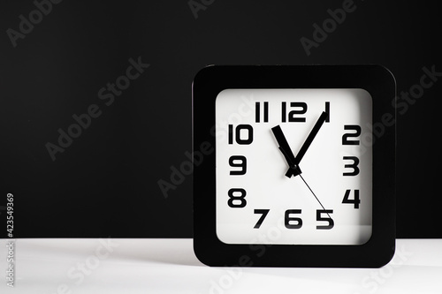 black square clock on white table, gray background, empty space, place for text