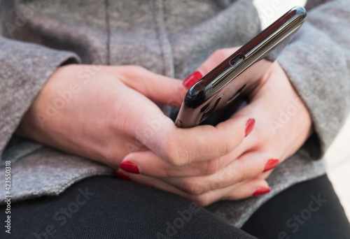Black smartphone in the hands of a young woman