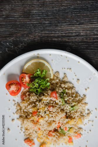 a plate with kenoa salad and vegetables on the background of a wooden table top photo