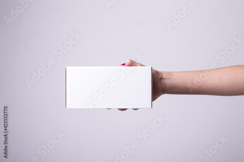 white cardboard box in female hands. side view, delivery, package, order