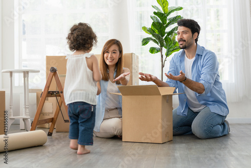 Little girl helping her parents packing boxes for moving to new house..Father and mother have happy looking their daughter © Supachai