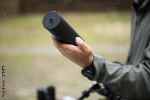 Military holds a pistol with a silencer.