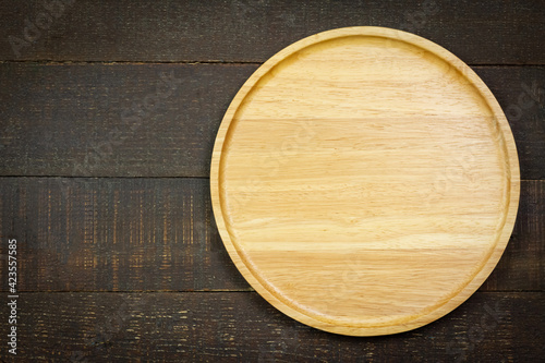 Empty wooden plate on rustic wooden background, top view.