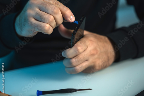 close up shot of a male technician fixing the screen and battery of a smart phone