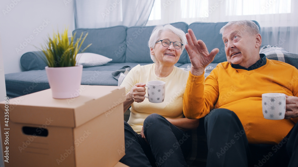 Happy retired couple relocating to new appartment. Drinking coffee surounded by cardboard boxes. buying new property. High quality photo Happy retired couple relocating to new appartment. Drinking coffee surounded by cardboard boxes. buying new property. High quality photo