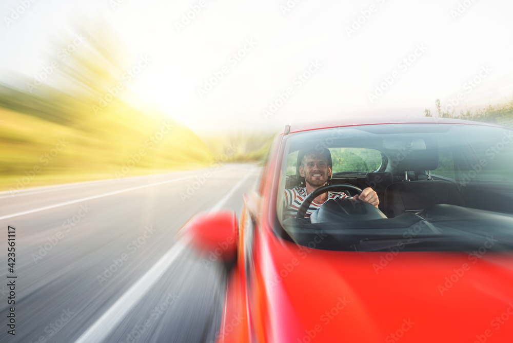 Man with a beard driving a car.
