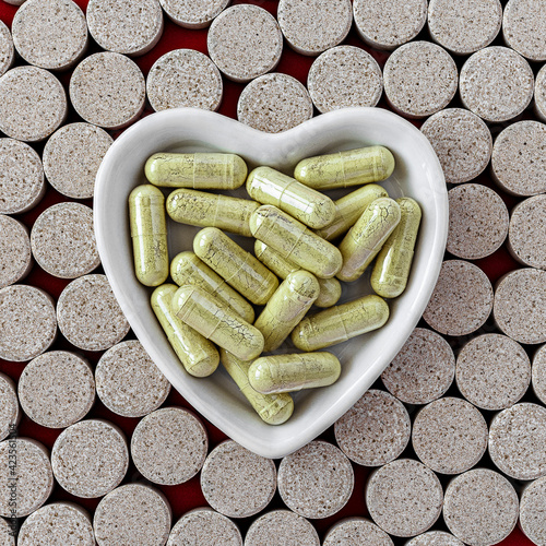 dietary concept. heart shaped white porcelain bowl full of rutin capsules, on a background of DGL chewable tablets. dietary supplement topview photo