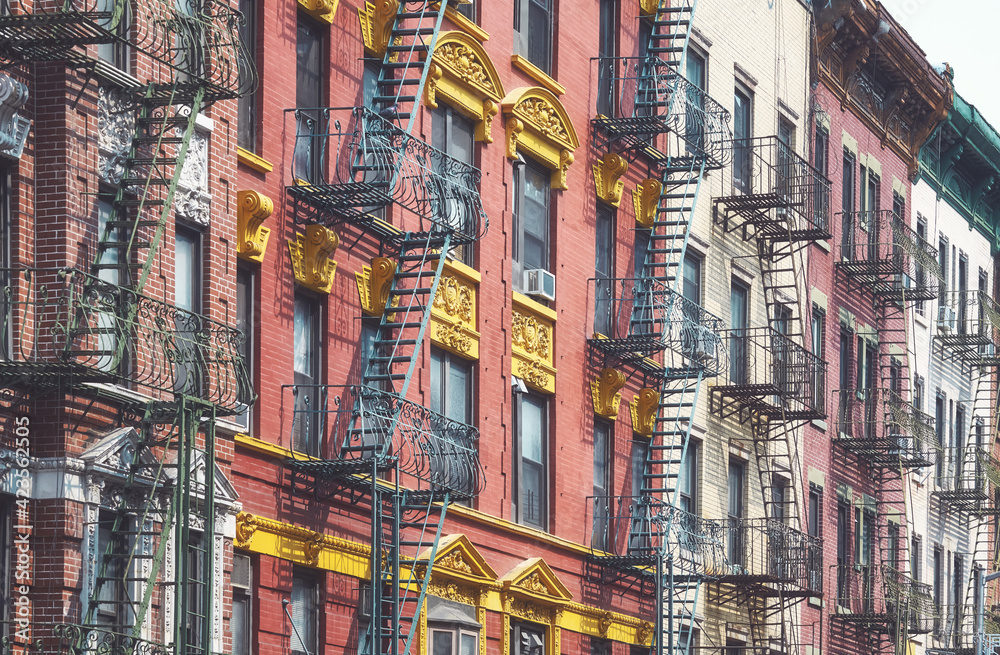 Row of old buildings with iron fire escapes, color toning applied, New York City, USA.