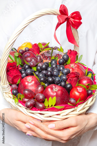 Wicker basket in hands with fruit and a bottle of wine  For a holiday or a picnic.