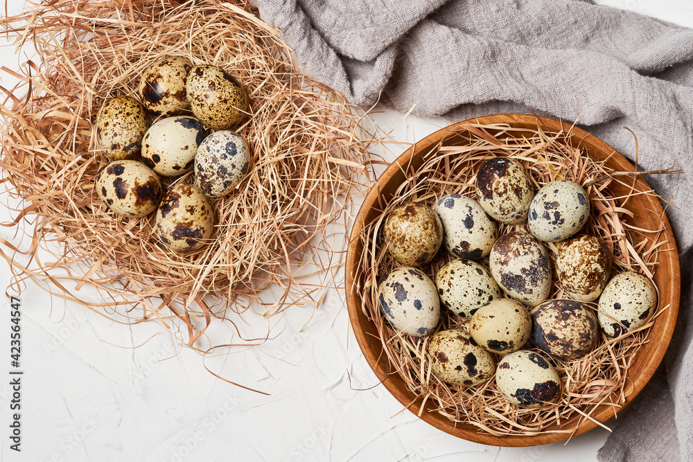 Obraz premium top view quail eggs in wooden bowl and nest on white table background 
