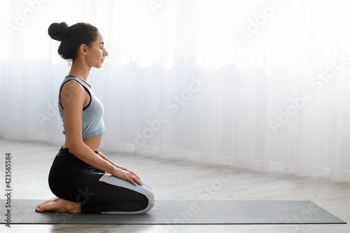 Peaceful young woman practicing yoga at home, meditating