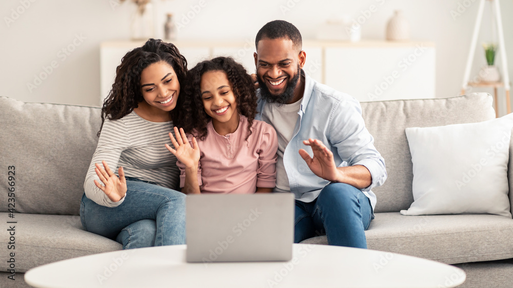 Black family having video call using laptop waving hands