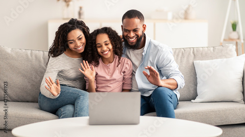 Black family having video call using laptop waving hands