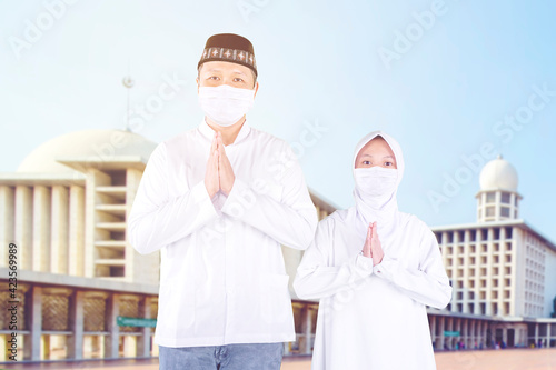 Child and father in mask congratulate Eid Mubarak