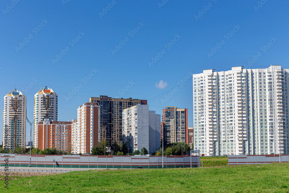 A new residential area with high-rise tenement buildings set against a bright blue sky. Summer, day, sunshine. A new residential area with high-rise tenement buildings set against a bright blue sky. Summer, day, sunshine.