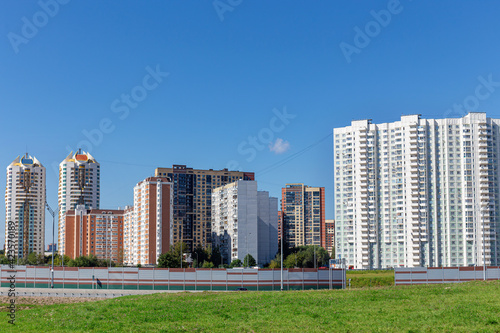 A new residential area with high-rise tenement buildings set against a bright blue sky. Summer  day  sunshine.