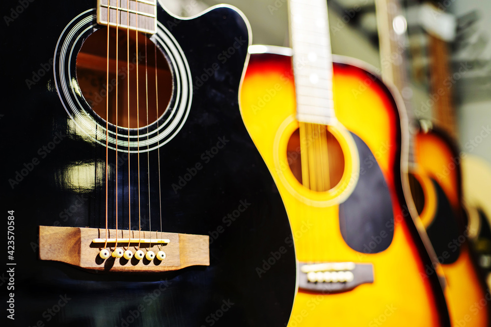Fototapeta premium Wooden guitars of different shapes and colors. Trade in acoustic instruments in a shop. Close-up