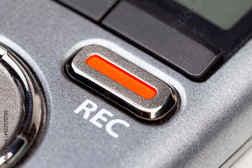 Red REC recording button on a modern pocket audio voice recorder, switch object macro extreme closeup Secretly recording, journalist or reporter equipment, simple live music recording abstract concept photo