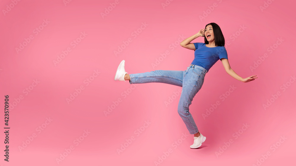 Happy young asian woman jumping at pink studio, copy space