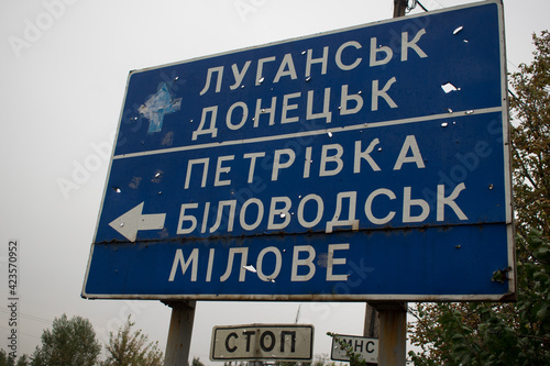 The road sign with the fragments of the projectile indicating the cities in the Ukrainian language 