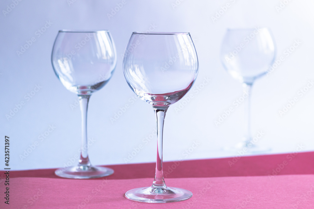 Empty wine glasses on white, rose, red paper background Empty wine glasses on white, rose, red paper background