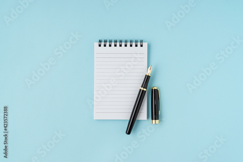 Notebook and pen on blue background. Copy space.