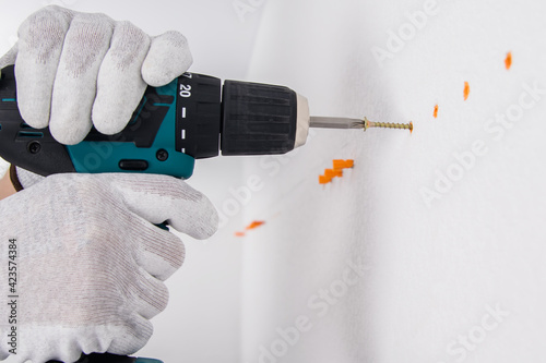 a screwdriver twists a self-tapping screw into a cork in a concrete wall close-up